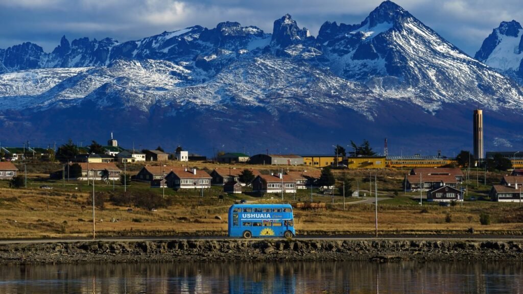 Ushuaia cityscape with a blue bus and stunning snowy mountain backdrop in Argentina.
